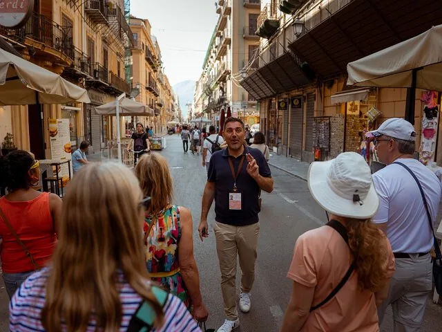 A tour guide addresses a group in a vibrant street.