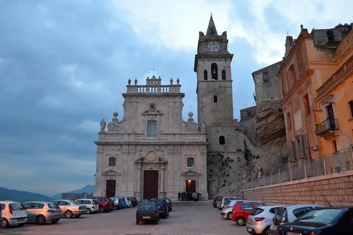 An old church with a tall bell tower and adjacent parking.